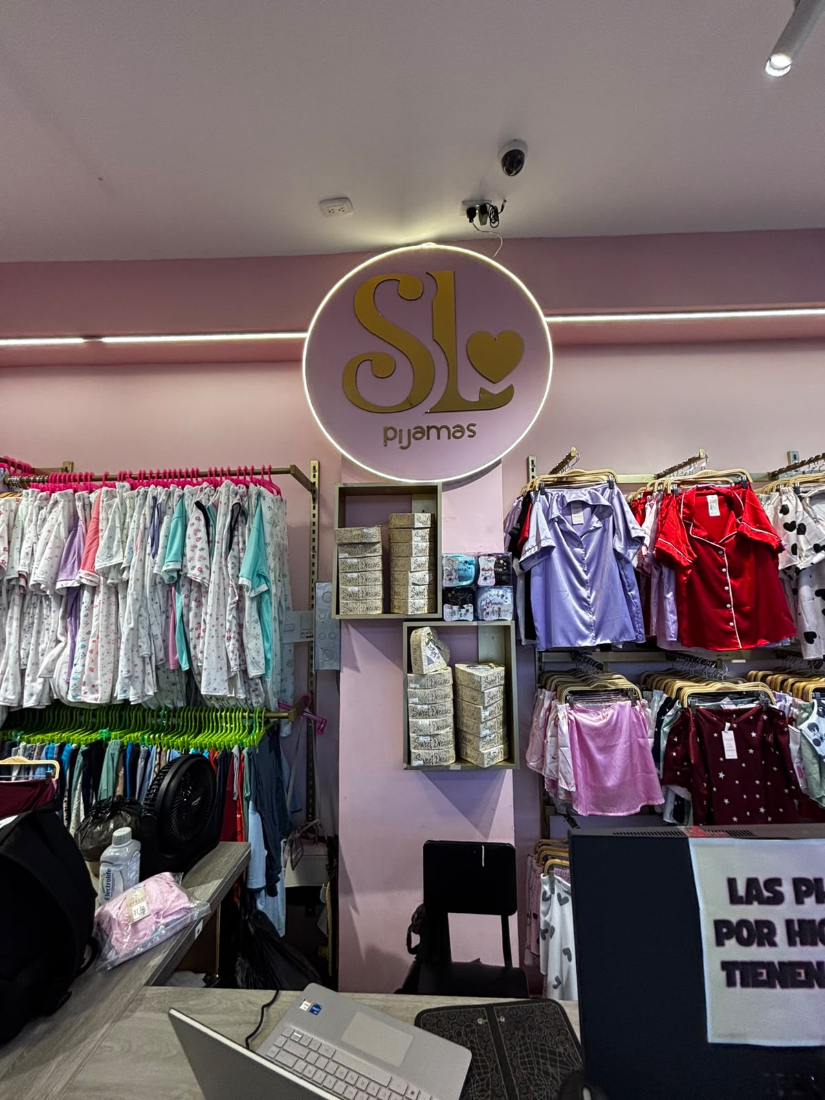 Letrero iluminado “SL pijamas” en la tienda de Cali